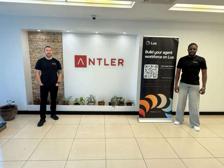 Two team members beside a Lua banner at an event space