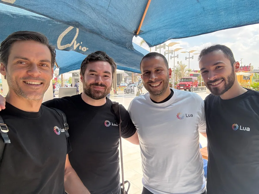 Four team members in Lua tees under cafe umbrellas in Cairo